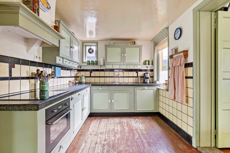 De eetkeuken heeft een plankenvloer, nostalgische wandtegels en een stucwerk plafond. De keukeninrichting is voorzien van een terrazzo aanrechtblad met RVS gootsteen, een vaatwasser, een combimagnetron, een inductiekookplaat en een koelkast. 