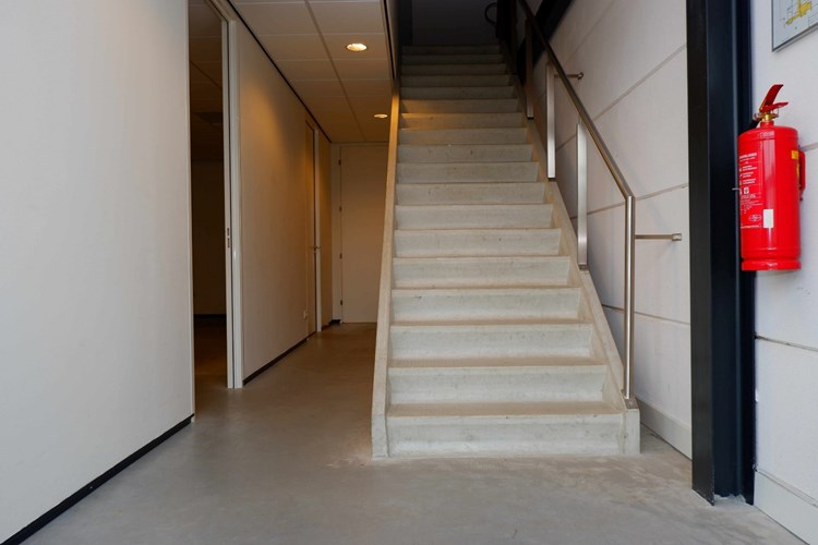 Via een gezamenlijke voordeur naar de gang met een betonnen trap. Deze geeft toegang tot de 1e verdieping met o.a. een drietal kantoorruimten, serverruimte en toiletruimte. 