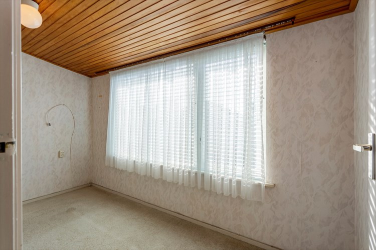 Slaapkamer III, gelegen aan de voorzijde. Met vloerbedekking, behangen wanden en een schroten plafond. Met een muurkast. Daglicht via een houten raamkozijn met dubbele beglazing en een vliegenhor.