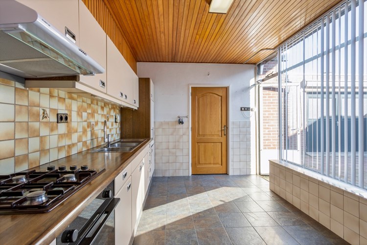 De keuken is voorzien van een tegelvloer, gedeeltelijk betegelde wanden en een schroten plafond. 
De keuken wordt verwarmd door een gas gevelkachel. Veel daglicht en een mooi zicht op de achtertuin via aan stalen raamkozijn. 