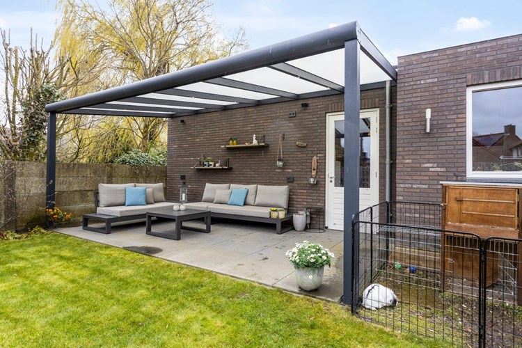 Aan de zijgevel van de garage bevindt zich een aluminium terrasoverkapping met polycarbonaat dakplaten en inbouwspots. Afmeting ca. 6,24 m. x 3,10 m.