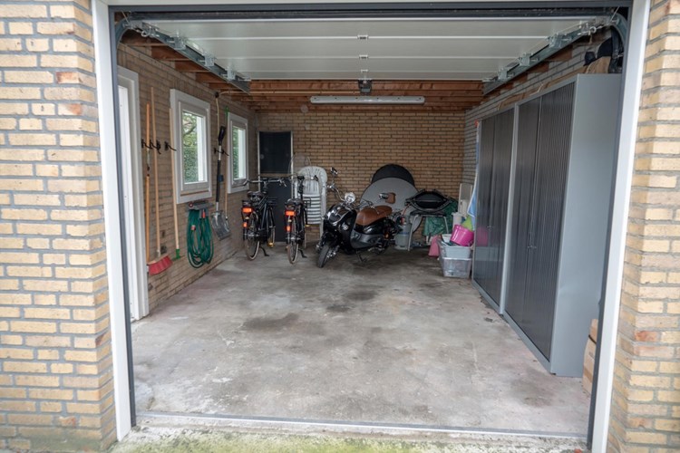 Vanaf de oprit is de garage bereikbaar via een op afstand te bedienen sectionaaldeur. Afmeting ca. 6,10 m. x 3,75 m. Met een betonvloer, halfsteens gevels en een plat bitumen dak. Voorzien van elektra. Daglicht via een kunststof deur en een tweetal kunststof kozijnen met dubbele beglazing. 