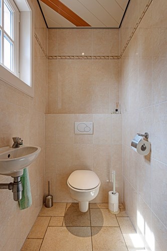 Het toilet is volledig betegeld en voorzien van vloerverwarming en een aluminium plafondafwerking met inbouwspot. 
Met een wandcloset en een opzetplateau.