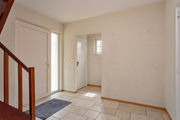 Via een kunststof voordeur toegang tot de ruime hal met een lichte tegelvloer met vloerverwarming, spachtelputz wanden en een stucwerk plafond.