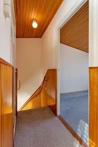 Vanuit de entree met een, met vloerbedekking beklede, trap met bordes naar de overloop. De overloop is voorzien van vloerbedekking, behangen wanden met lambrisering en een schroten plafond. 
