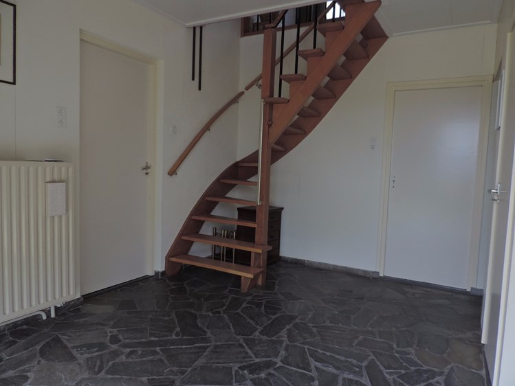 lichte ruime entree met natuursteen vloer en open trap