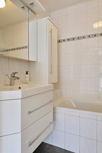 Verder een badmeubel met een wastafel en een spiegelkast met inbouwverlichting. 