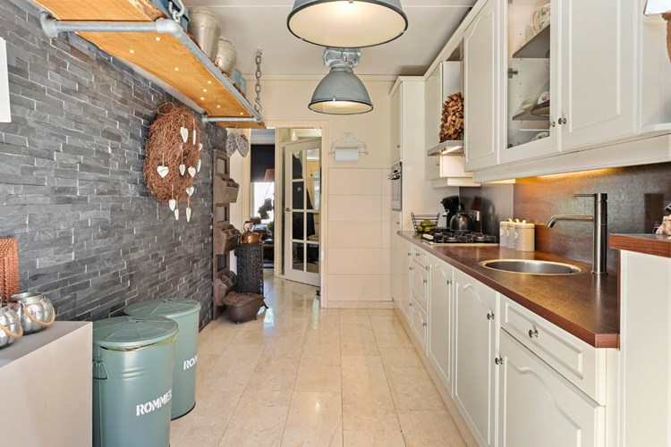 De keuken staat in open verbinding met de woonkamer en de serre. Met een marmeren tegelvloer met vloerverwarming, een met antraciet leistenen beklede wand en een stucwerk plafond.  