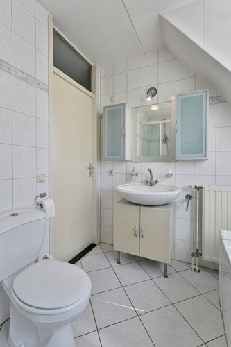 De badkamer is volledig licht betegeld met een spuitwerk plafond. Voorzien van een badmeubel met wastafel, een 2e toilet en mechanische ventilatie. 