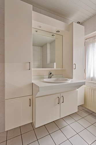 Verder een badmeubel met een vaste wastafel en een spiegel. Natuurlijke ventilatie middels een raamkozijn met enkele beglazing en een rolluik. 