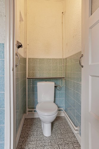 In de bijkeuken ligt ook het gedeeltelijk betegeld toilet met een tegelvloer. Voorzien van een duoblok.