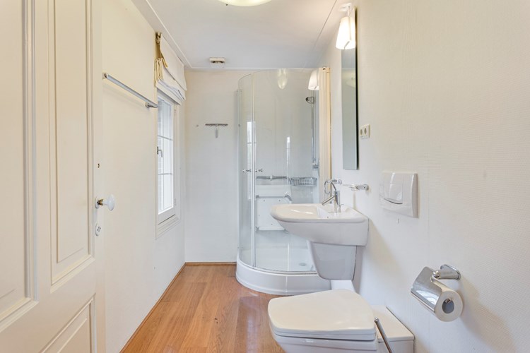 Er is nog een 2e  badkamer aanwezig met een parketvloer en een raamkozijn. Voorzien van een douchecabine, een wandcloset en een wastafel. 