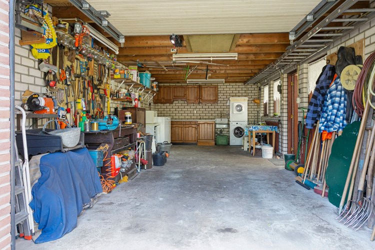 De, te verwarmen, garage is volledig geïsoleerd. Met een betonvloer, spouwmuren en een zadeldak. Verder een uitstortgootsteen, een keukenblok en radiatoren. Hier bevinden zich ook de aansluitingen voor de wasapparatuur. Via een vlizoluik naar een volledig begaanbare zolderberging. 