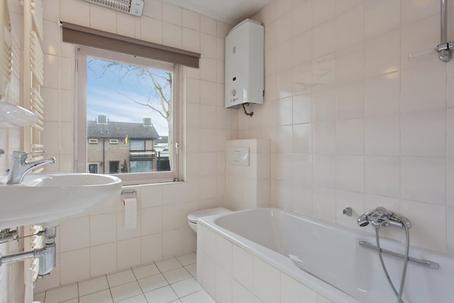 De badkamer is geheel betegeld en beschikt over een ligbad, wastafel en tweede toilet. De oude warmwatervoorziening is niet meer in gebruik.
