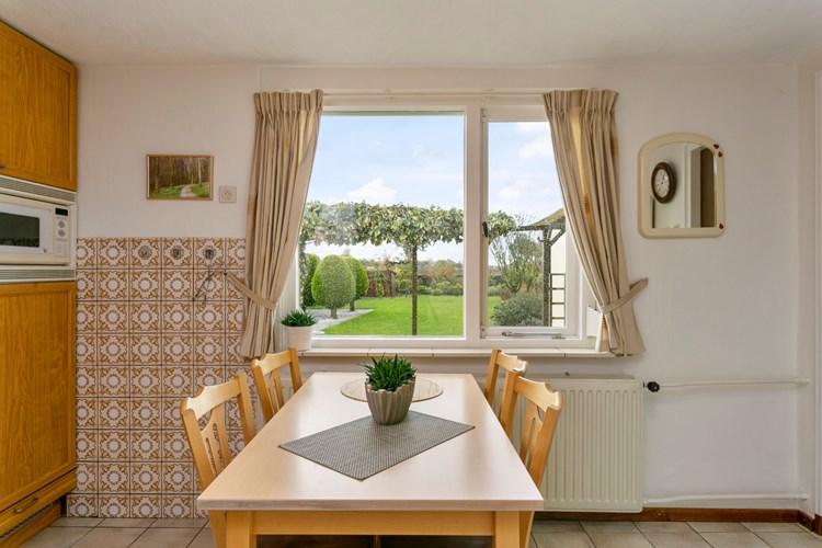 Vanuit de keuken een mooi zicht op de vrije achtertuin via een groot raamkozijn met dubbele beglazing en een zonnescreen.