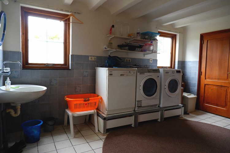 De bijkeuken met een tegelvloer is voorzien van de aansluiting voor de wasapparatuur en een wasbak. 