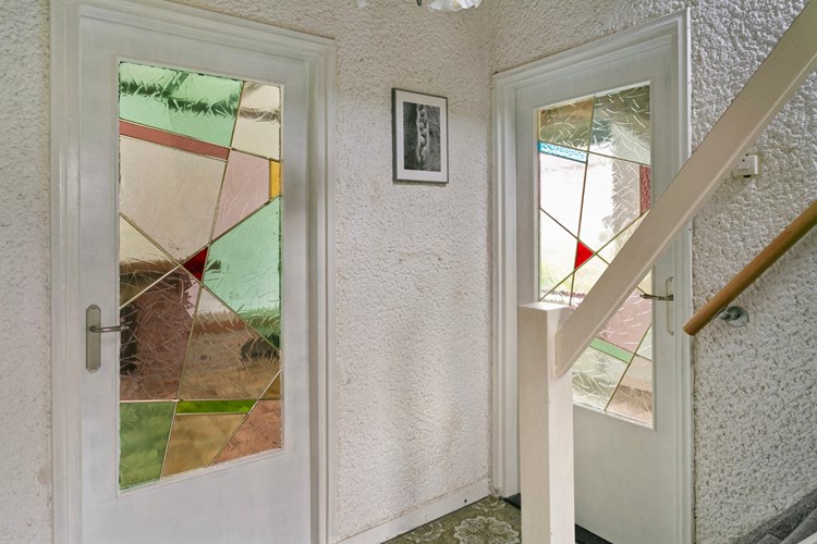 Vanuit de hal toegang tot zowel de keuken als de woonkamer via een deur met mooie glas-in-lood ramen.