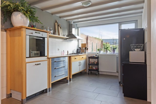 De moderne keuken in wandopstelling is voorzien van diverse inbouwapparatuur waaronder een oven, gasfornuis, afzuigschouw en vaatwasser.