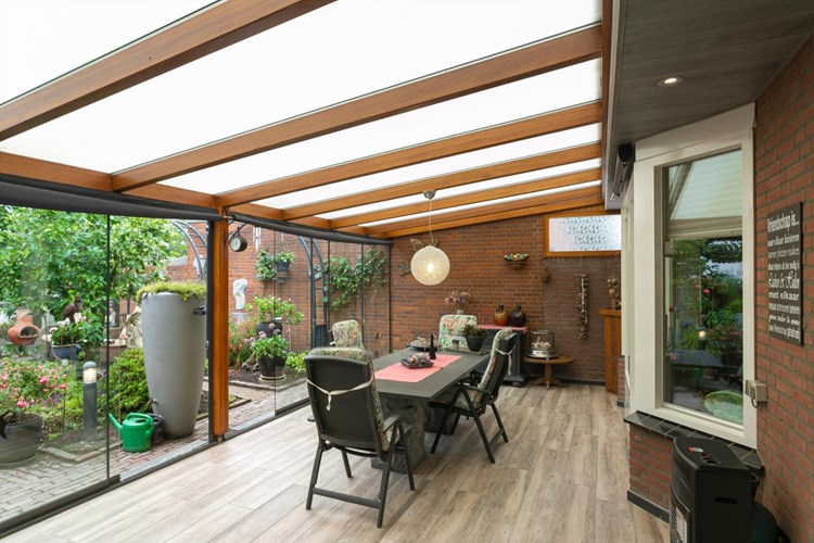 Tuinkamer / overdekt terras met een 'houtlook' tegelvloer, hardhouten dakconstructie met polycarbonaat dakplaten. 
