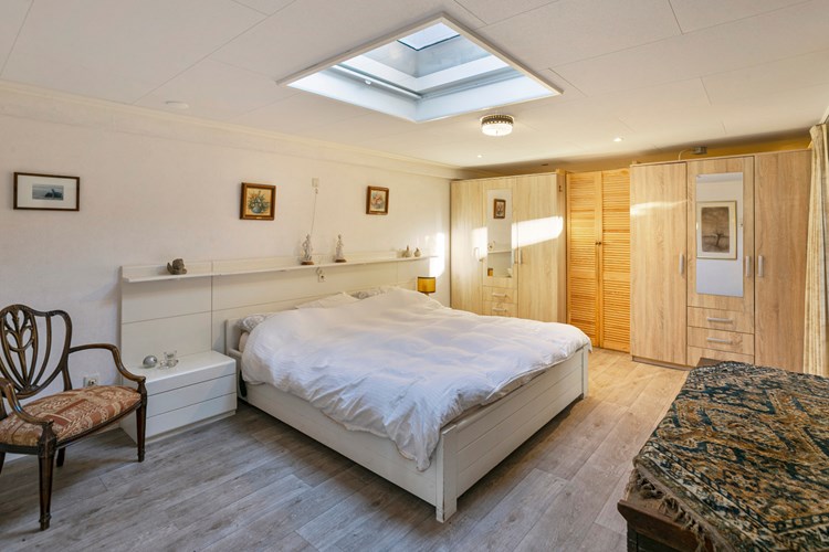 Slaapkamer met een vinylvloer, behang wanden en een panelen plafond met een lichtkoepel en een verduisteringsgordijn. Met een losse kastenwand en een elektrische radiator. 
