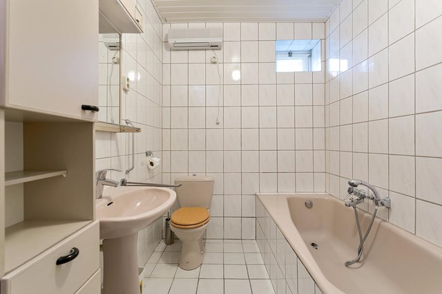 De badkamer is geheel betegeld en voorzien van een tweede toilet, wastafel, ligbad en badmeubel.