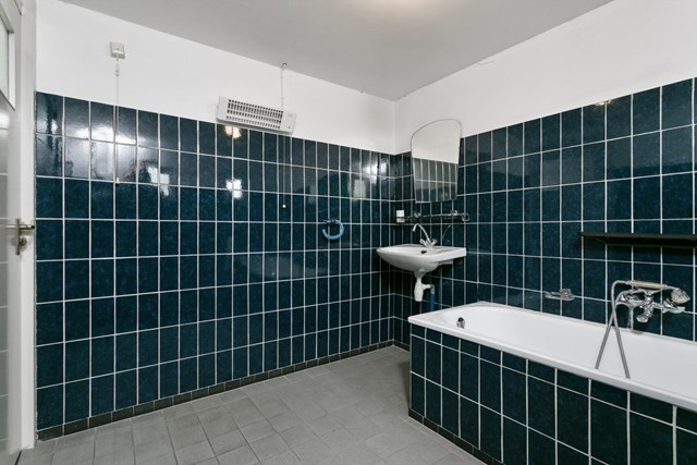 De grotendeels betegelde badkamer is voorzien van een ligbad, wastafel en separate douche. 