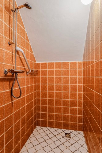 Separate doucheruimte met een lichte tegelvloer, volledig betegelde wanden en een stucwerk plafond. Voorzien van een thermostaatkraan. 