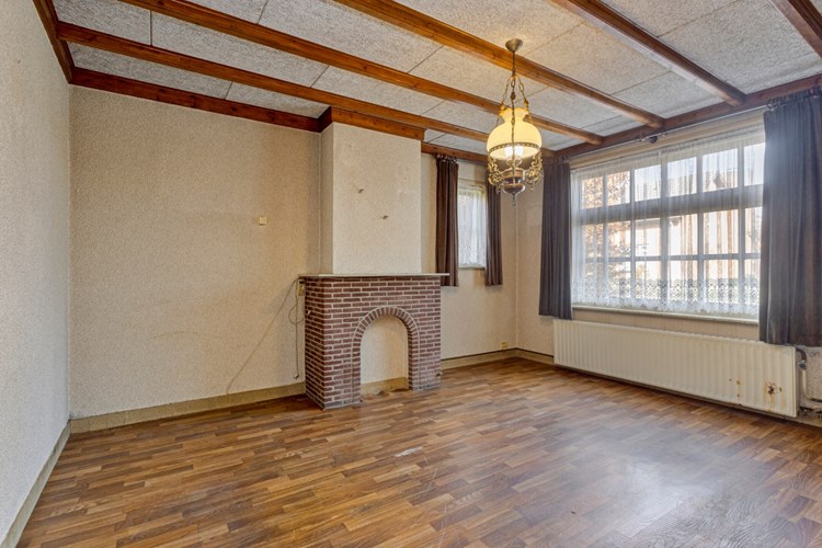 De aangebouwde woonkamer is voorzien van een vinylvloer, stucwerk wanden en een houten balkenplafond met vezelplaten. Veel daglicht. 