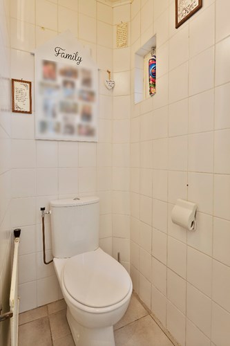 Toilet met een tegelvloer, volledig licht betegelde wanden en een MDF plafond. Voorzien van een duoblok. Natuurlijke ventilatie middels een raampje. 