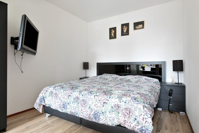 De slaapkamer heeft dezelfde laminaatvloer en schuur-/spuitwerk wand- en plafondafwerking