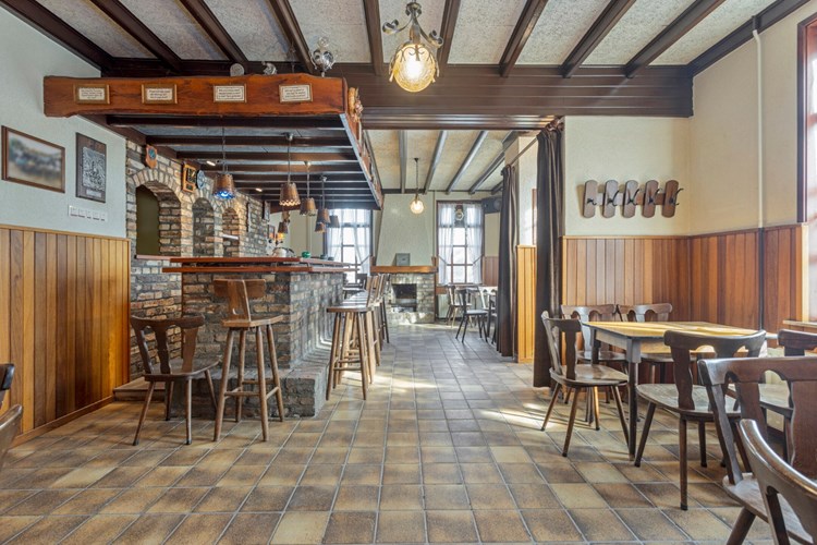 Via een houten deur naar een portaal met de meterkast. Het sfeervolle café gedeelte is voorzien van een tegelvloer, houten lambrisering en een houten balken plafond met vezelplaten.