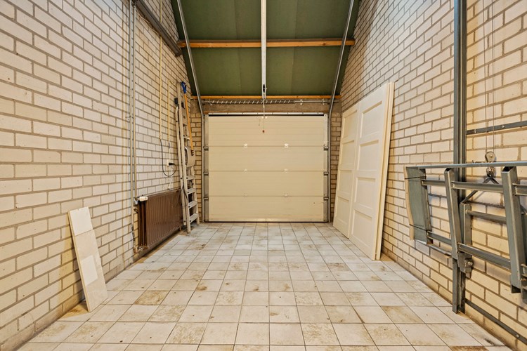 De garage is bereikbaar via een op afstand te bedienen sectionaaldeur. Met dakisolatie,  een tegelvloer, een radiator en een uitstortgootsteen. Hier bevindt zich ook de aansluiting voor de wasapparatuur. 