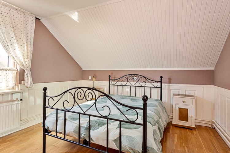 Slaapkamer gelegen aan de achterzijde, met een eiken lamel parketvloer, lambrisering wanden en een spuitwerk- en schroten plafond. 