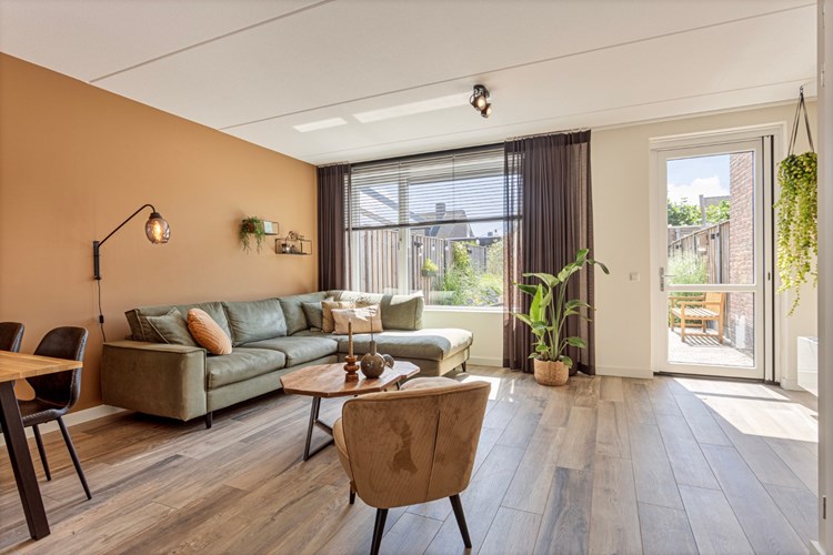 De ruim opgezette woonkamer heeft een 'houtlook' tegelvloer met vloerverwarming, vlak stucwerk wanden en een spuitwerk plafond.
