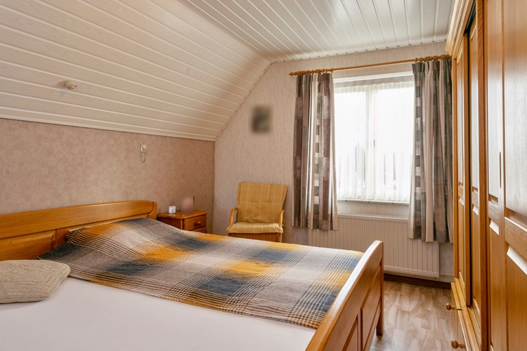 Slaapkamer gelegen aan de voorzijde, met een vinylvloer, behangen wanden en een kunststof schroten plafond. 