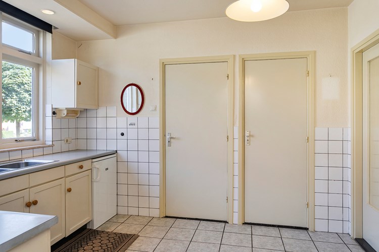 Het keukenmeubel is voorzien van een dubbele RVS spoelbak, een RVS gaskookplaat (5 pits), een afzuigkap en een koelkast. Verder een praktische muurkast en een deur naar de bijkeuken en toilet.