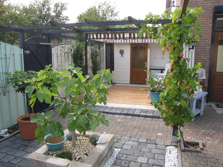 de buitenleeftuimte met decking-terras, tuinberging en aankleding "in spaanse sfeer"