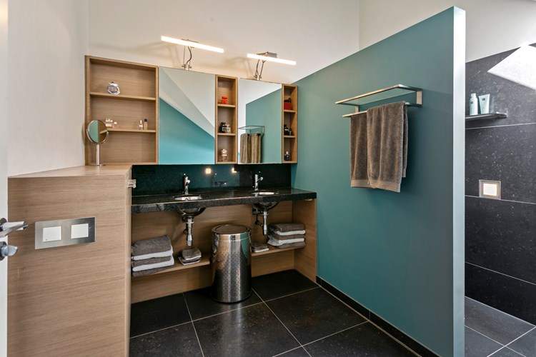 De badkamer is voorzien van een tegelvloer met vloerverwarming, stucwerk wanden en -plafond. Een badkamermeubel met een granieten blad met twee RVS waskommen en spiegelkasten met verlichting. 