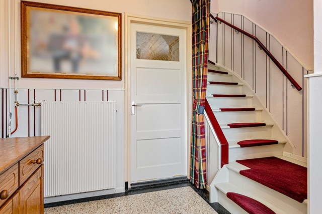 Entree met trapopgang en toegangsdeur naar de keuken. De karakteristieke vloer ziet u ook in de keuken terug.