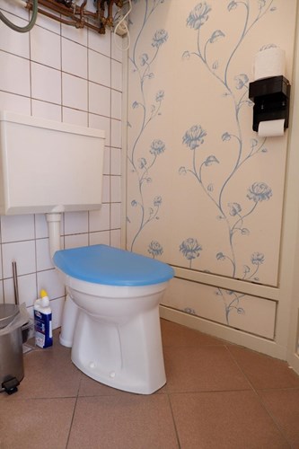 Het toilet is voorzien van een tegelvloer met vloerverwarming, Met een duoblok en een fonteintje.