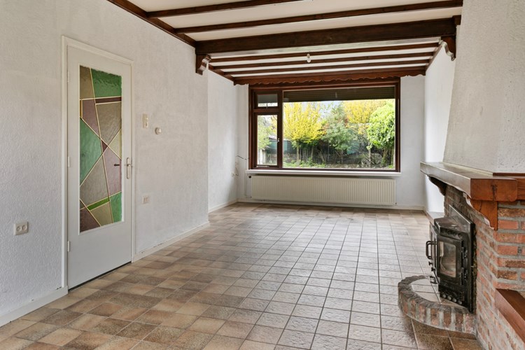 De uitgebouwde woonkamer is voorzien van tegelvloer, granol wanden en een sierbalken plafond. 