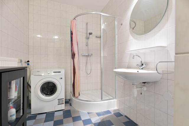 De badkamer is geheel betegeld en heeft een wastafel, douchecabine en aansluiting voor de wasmachine