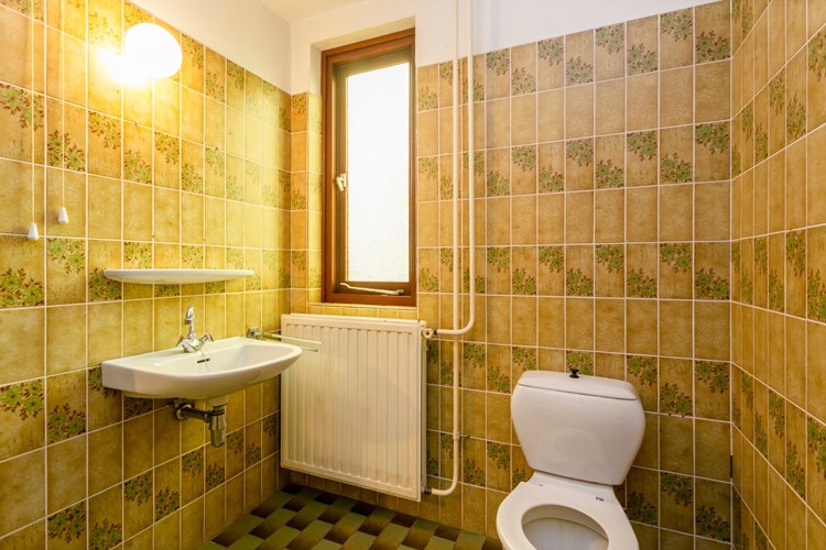 Badkamer met een tegelvloer, grotendeels betegelde wanden en een stucwerk plafond. Met een 2e toilet en een vaste wastafel. 