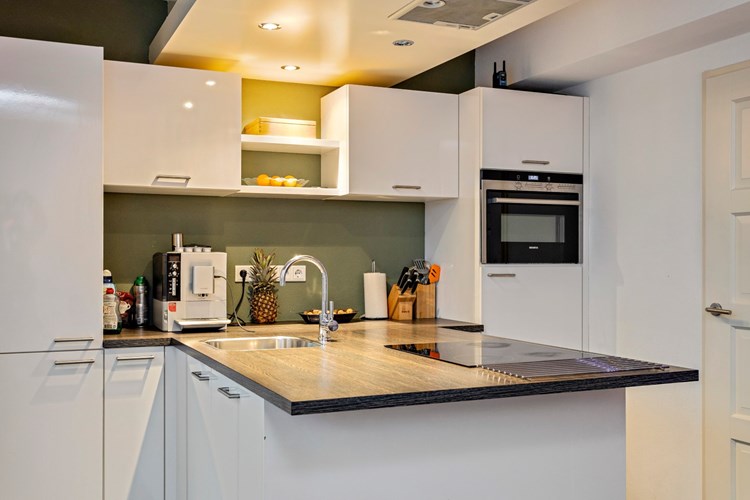 De moderne keukeninrichting (2014) is voorzien van een inductiekookplaat met een afzuigkap en inbouwspots in het verlaagde plafond, een RVS spoelbak, een koelkast, een combimagnetron en een vaatwasser.