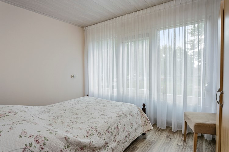 Slaapkamer gelegen aan de voorzijde, met een laminaatvloer, behang wanden en een MDF plafond. Daglicht via een kunststof raamkozijn (draai-/kiep) met dubbele beglazing en een rolluik. 