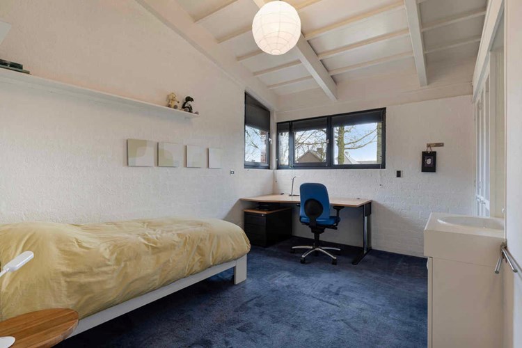 Slaapkamer, gelegen aan de voorzijde, met vloerbedekking en een hoog oplopend plafond. Met een vaste inbouwkast en een wastafel. Daglicht via een hardhouten raamkozijn met dubbele beglazing. 