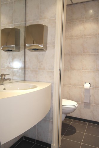 Het gezamenlijk toilet op de 1e etage is volledig betegeld en voorzien van een wandcloset en een wastafel met grote spiegel. 