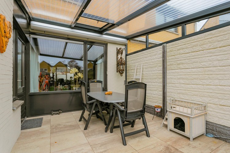 Direct aan de woning bevindt zich een aluminium terrasoverkapping met polycarbonaat dakplaten een een elektrisch bedienbare zonneluifel. Er is een te openen luik aanwezig.