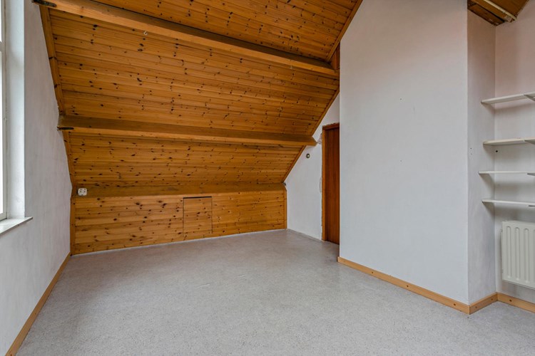 Vanuit de voorzolder via een deur naar een ruime 4e zolder-/slaapkamer. Met een vinylvloer, stucwerk wanden en een afgetimmerd dak. 