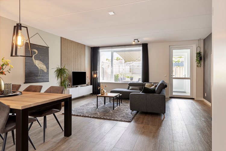 Sfeervolle woonkamer met een 'houtlook' tegelvloer met vloerverwarming, vlak stucwerk wanden en een spuitwerk plafond. 